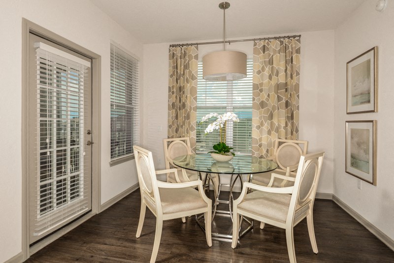a dining room with a glass table and chairs and a window