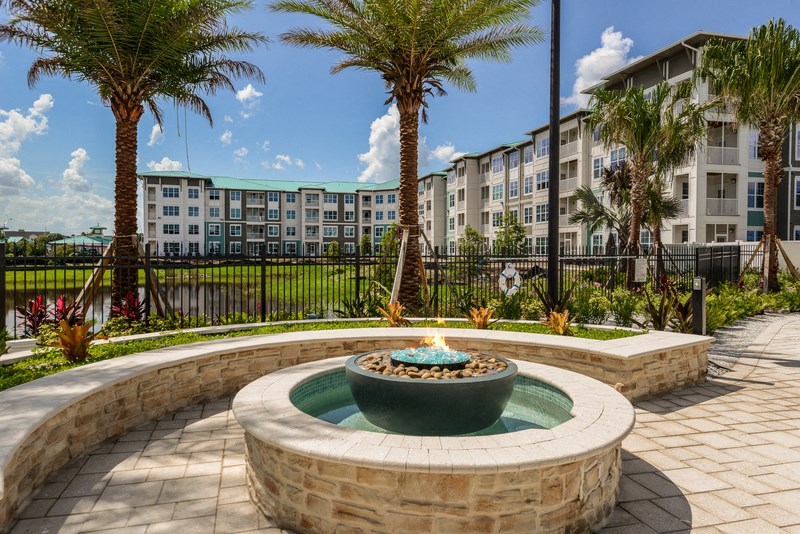 a fountain in front of an apartment building with palm trees