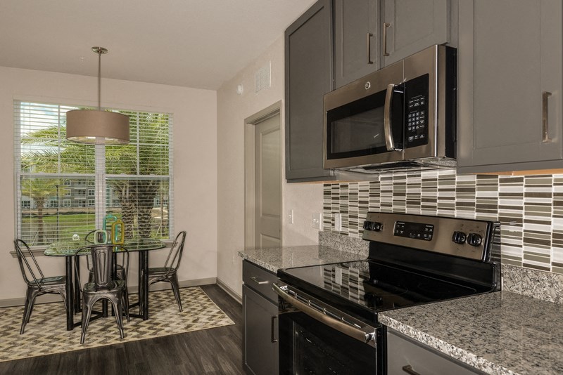 a kitchen with granite counter tops and black appliances and a dining room table