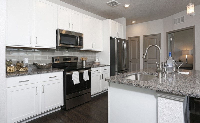 a kitchen with white cabinets and granite counter tops