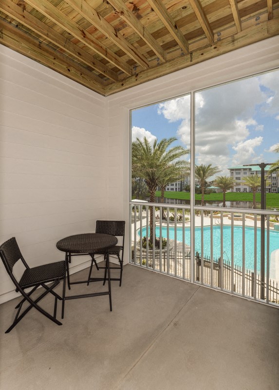 a balcony with a table and chairs and a view of a swimming pool