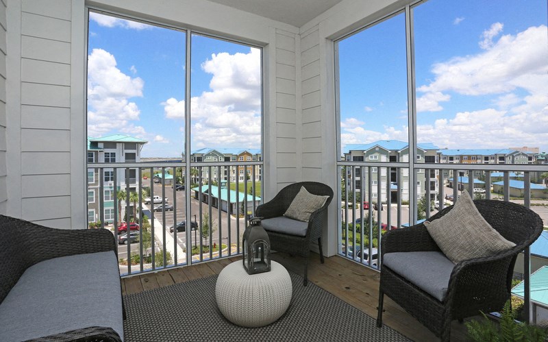 a living room with two chairs and a balcony overlooking the ocean