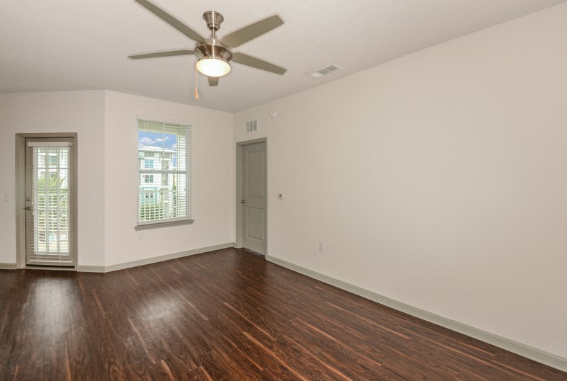 an empty living room with white walls and a ceiling fan