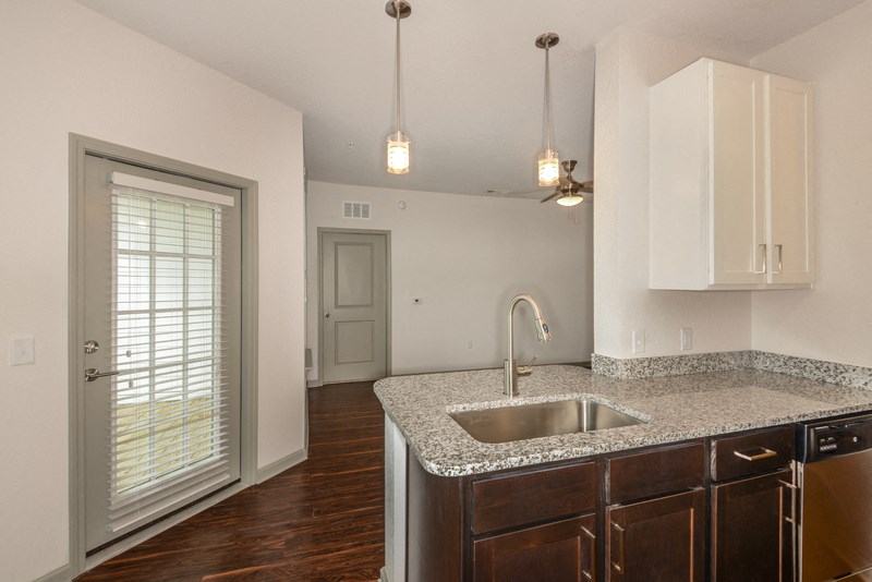 an empty kitchen with a sink and a door to a living room