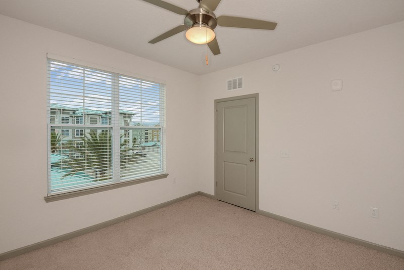 a living room with a large window and a ceiling fan