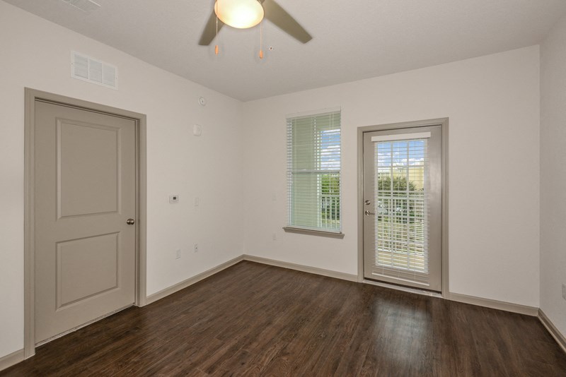 the living room of an empty house with a ceiling fan and a door