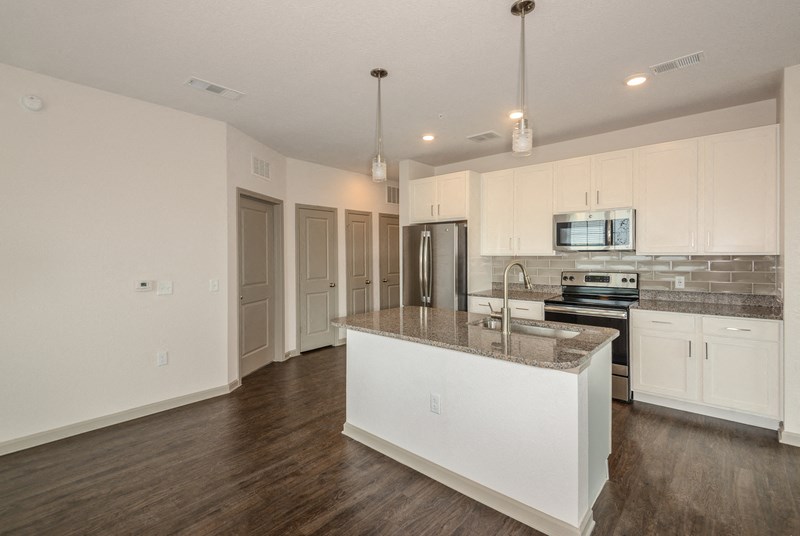 a kitchen with white cabinets and a marble counter top