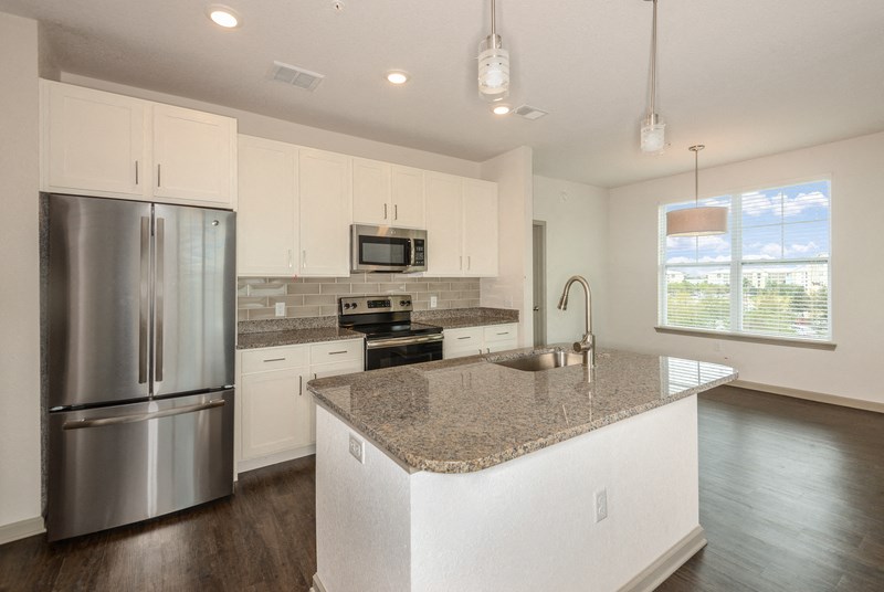 an open kitchen with granite counter top and stainless steel refrigerator