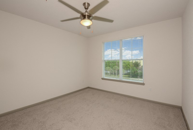 an empty living room with a ceiling fan and a window