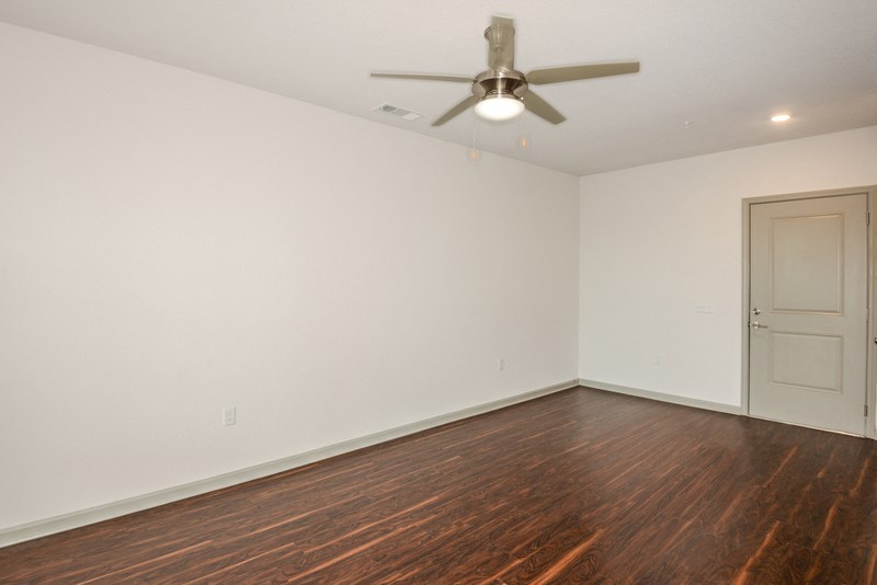 an empty living room with white walls and a ceiling fan