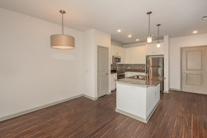 an empty living room with a kitchen with a counter top and