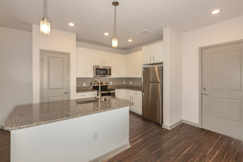 a kitchen with a granite counter top and a stainless steel refrigerator