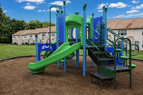 A playground with a green slide and a blue structure.