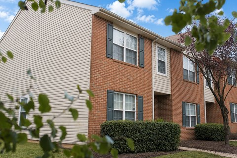 A red brick apartment building with green shutters on the windows.