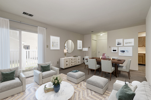 A living room with a white couch, a coffee table, and a dining table.