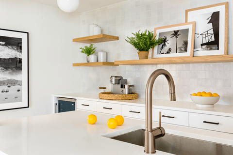 A modern kitchen with a stainless steel sink and wooden shelves.