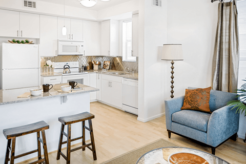 A kitchen with white cabinets and a blue couch.