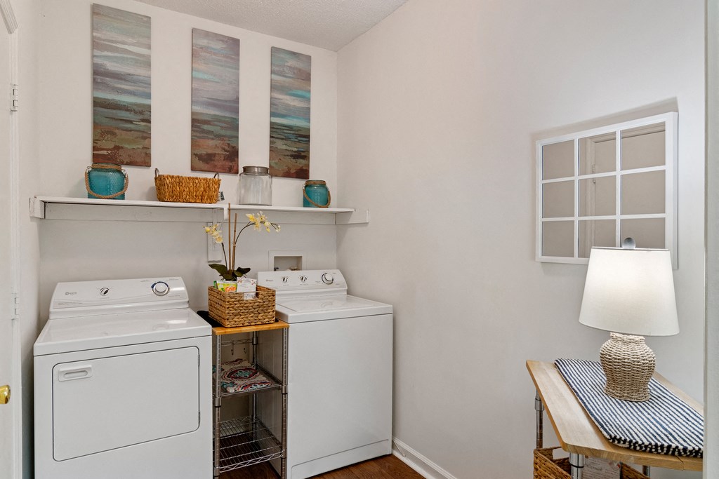 Laundry Room with a white washer and dryer, wood shelving and hardwood style floors.