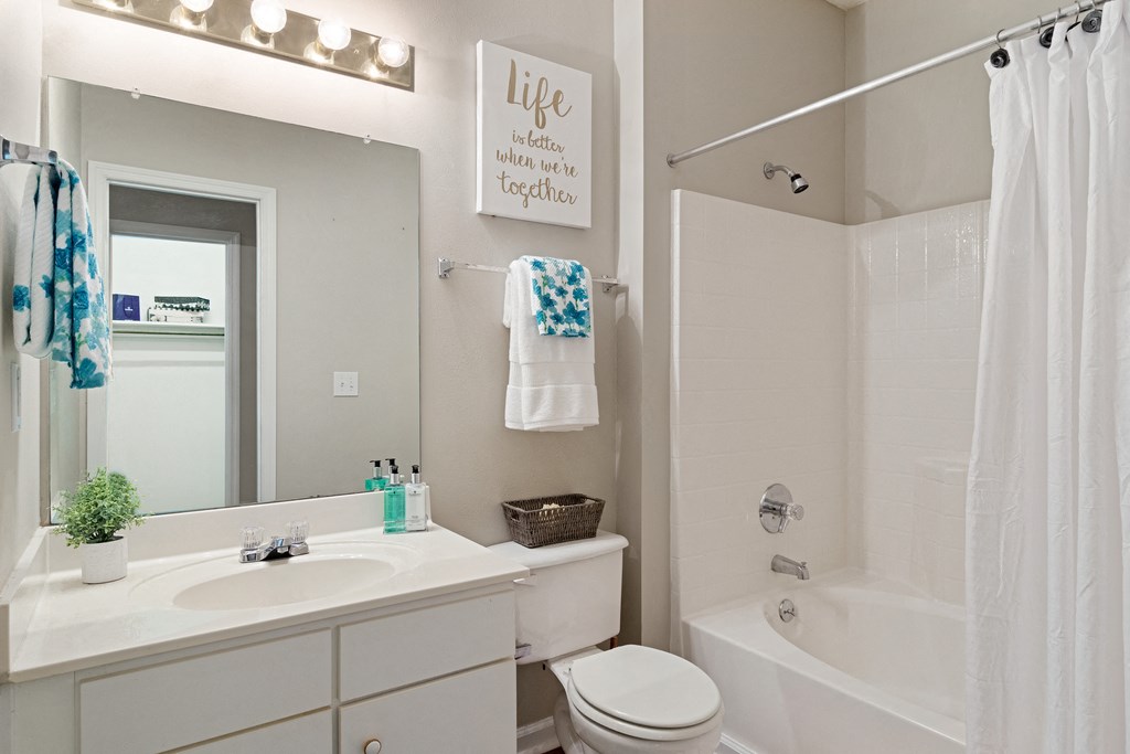 Bathroom with white cabinets with white countertops, white walls, and hardwood style flooring