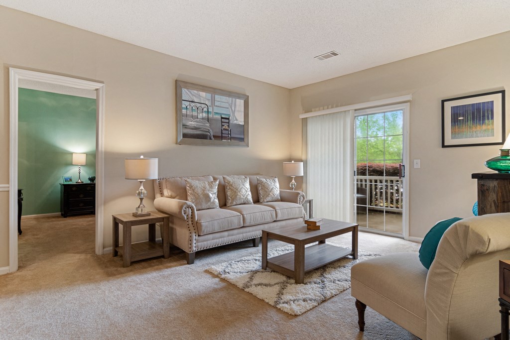 Living room with cream couch, coffee table, end tables, chaise lounge and the bedroom door in the background.