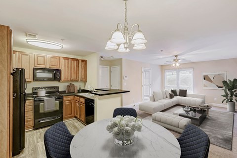 A kitchen with a table and chairs in the foreground and a living room in the background.
