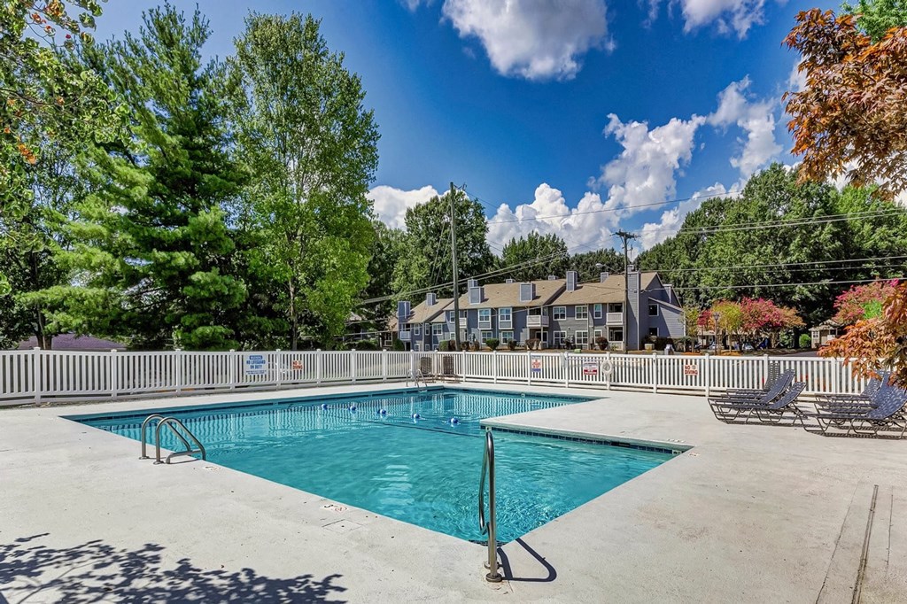 A large swimming pool surrounded by trees and a fence. at Brandemere Apartment Homes, Winston Salem, NC, 27106