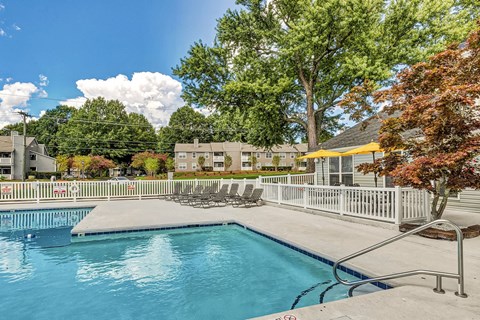 A swimming pool surrounded by a metal fence and chairs.