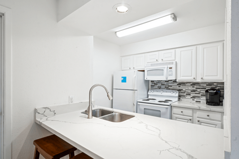 A kitchen with white cabinets and a white counter top.