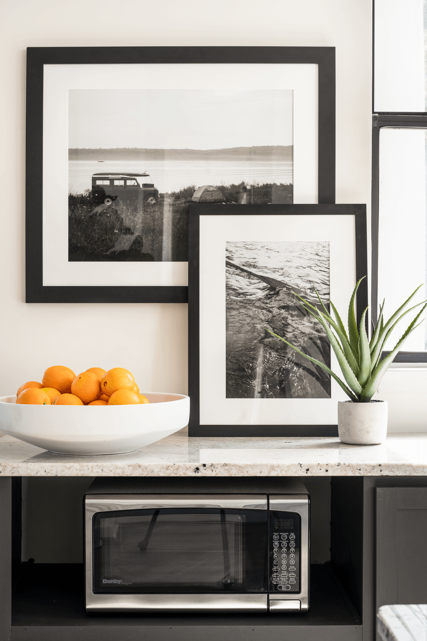a kitchen with black and white pictures on the wall and a bowl of oranges on the counter at Bridges at Mallard Creek Apartment Homes, Charlotte