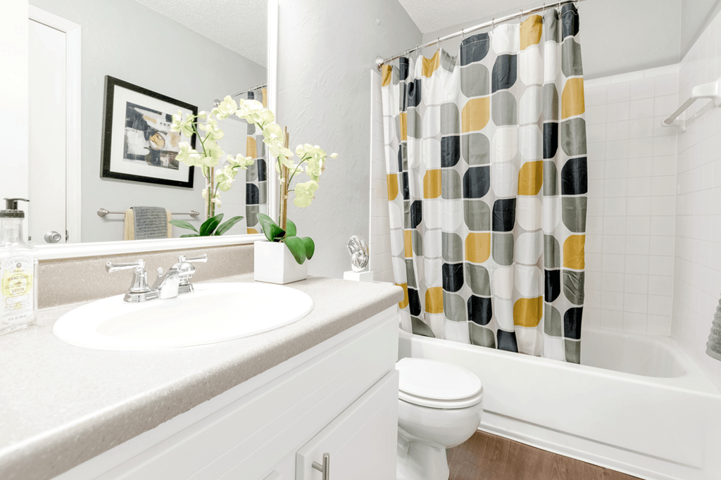 a bathroom with a white sink and toilet next to a bathtub with a shower curtain  at Bridges at Mallard Creek Apartment Homes, Charlotte, 28269