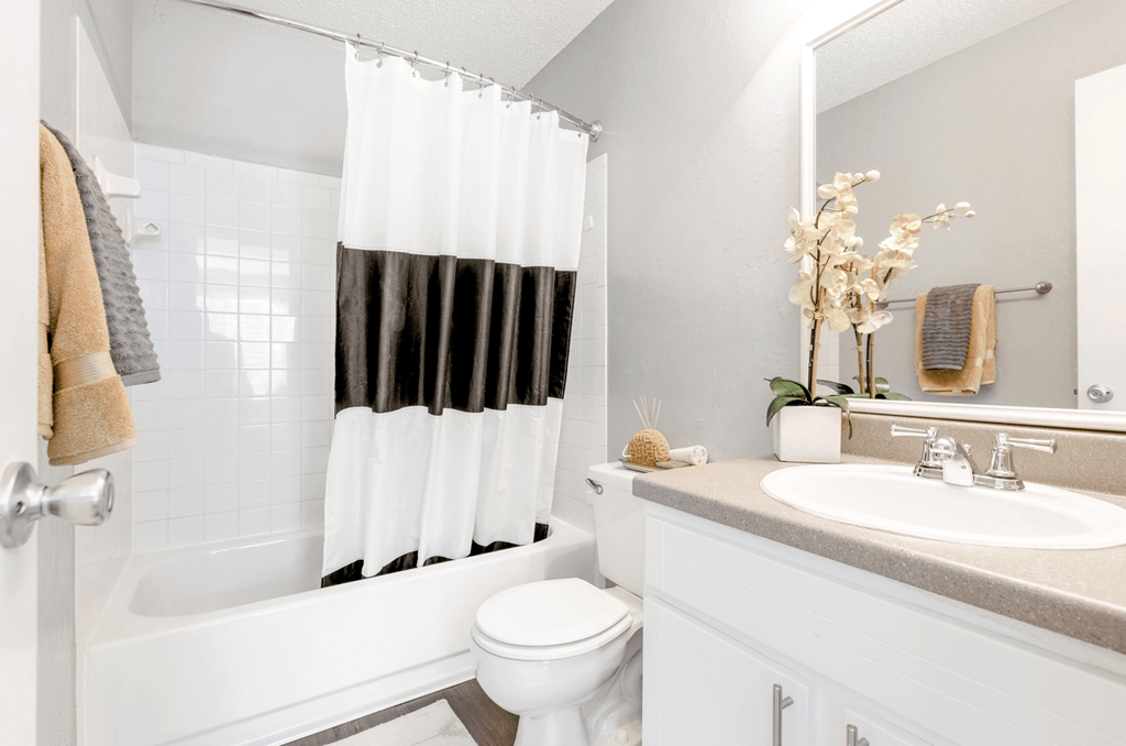 a bathroom with a white toilet next to a bathtub with a black and white shower curtain at Bridges at Mallard Creek Apartment Homes, Charlotte, NC, 28269