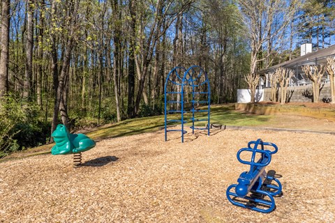 A playground with a blue swing set and a green slide.