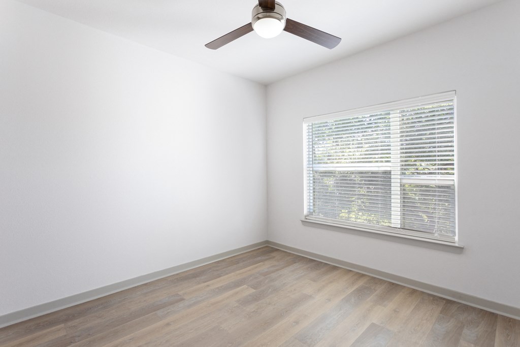 a bedroom with a large window and wood flooring