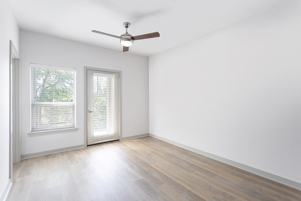 an empty living room with white walls and a ceiling fan