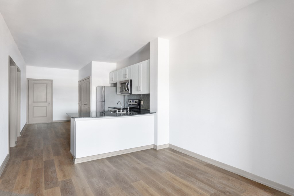 a living room and kitchen with white walls and wood floors