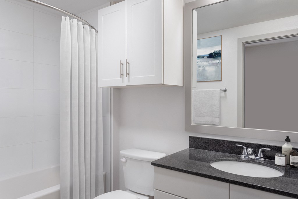 a bathroom with white cabinets and black countertop