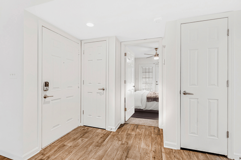 a bedroom with two doors and a bed in the background
