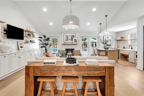 a kitchen and living room with a large wooden table in the middle of the room