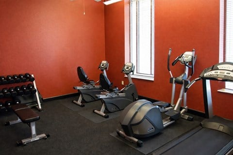 A gym with orange walls and a variety of exercise equipment.
