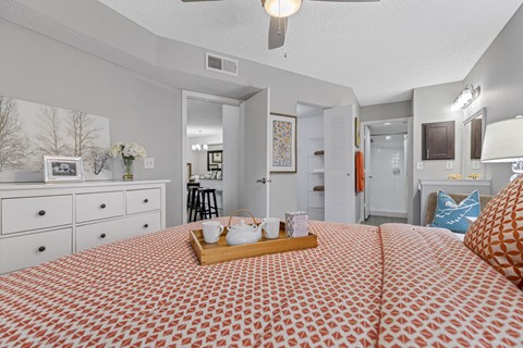 A bedroom with a bed, dresser, and ceiling fan.