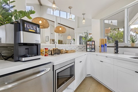 A modern kitchen with white cabinets and stainless steel appliances.