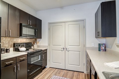 A kitchen with a white door and black cabinets.