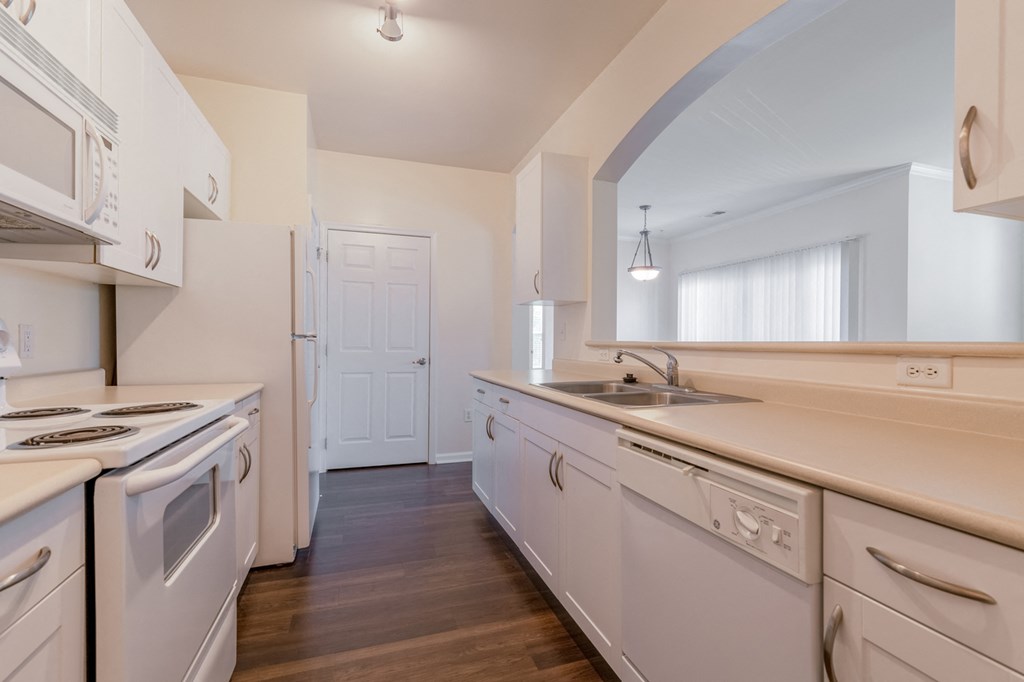 an empty kitchen with white cabinets and appliances and a sink