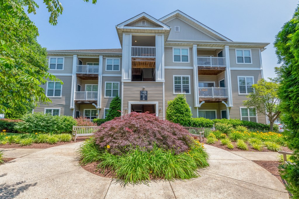 an apartment building with a flower garden in front of it
