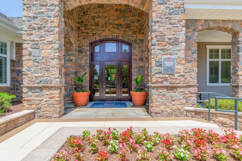 the front door of a leasing office with flowers in front of it