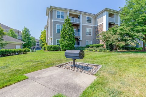 A mailbox sits in front of a grassy area with apartment buildings in the background.