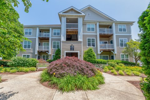 A large apartment building with a front garden and a statue.