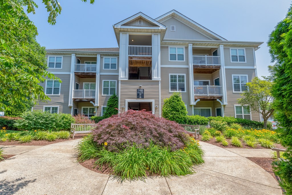 A large apartment building with a front garden and a plaque on the wall.
