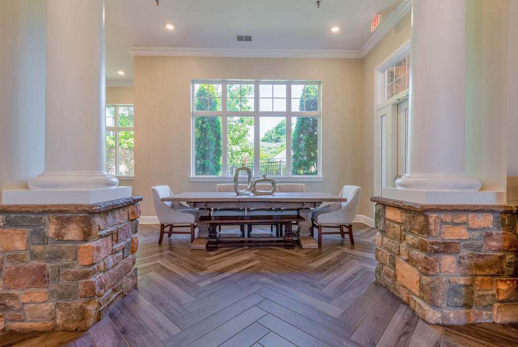A dining room with a table surrounded by chairs and a stone pillar.