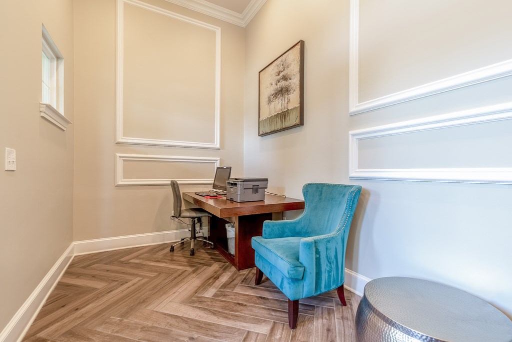 A room with a desk, chair, and picture on the wall.